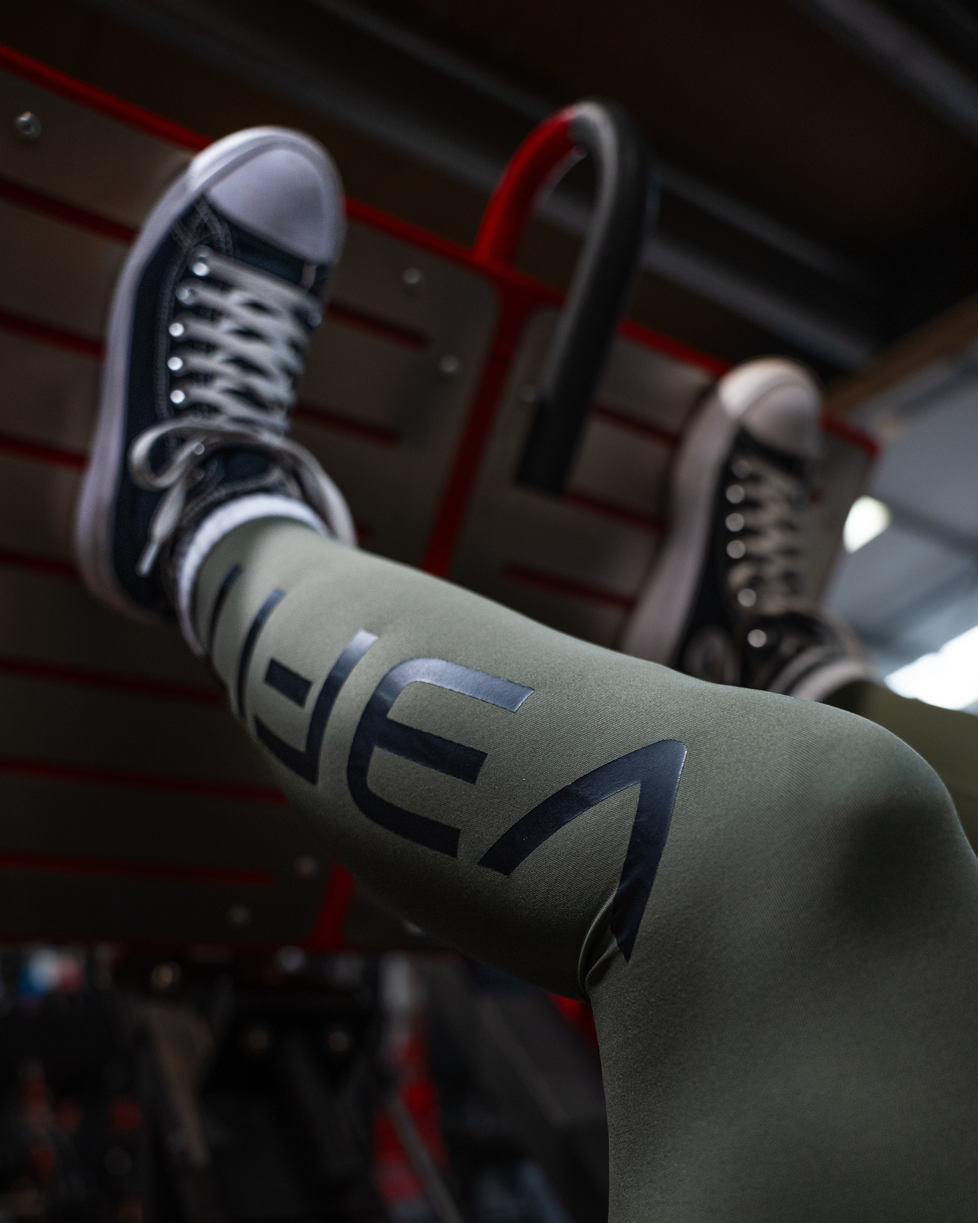 A photograph depicts a woman using a leg press machine at the gym, with the logo visible on her lower leg.